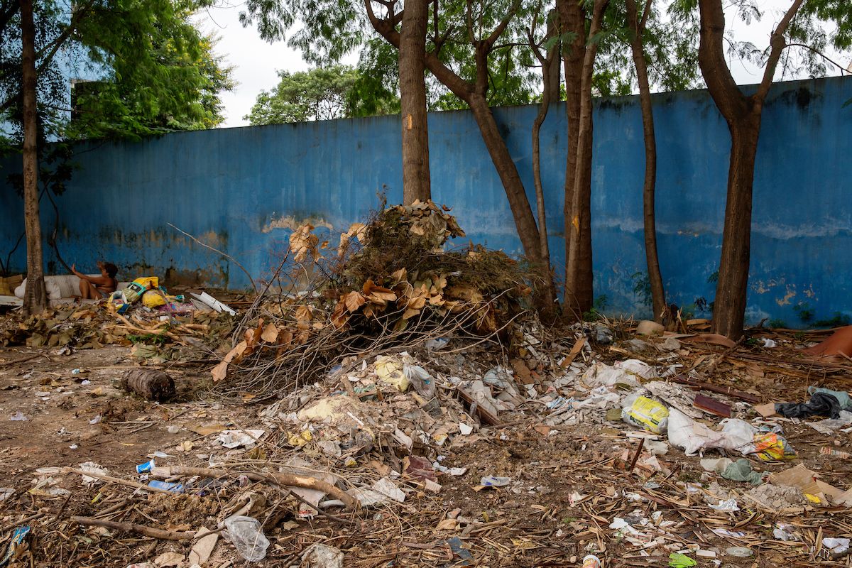 A pile of litter and leaves sits in front of a blue wall.